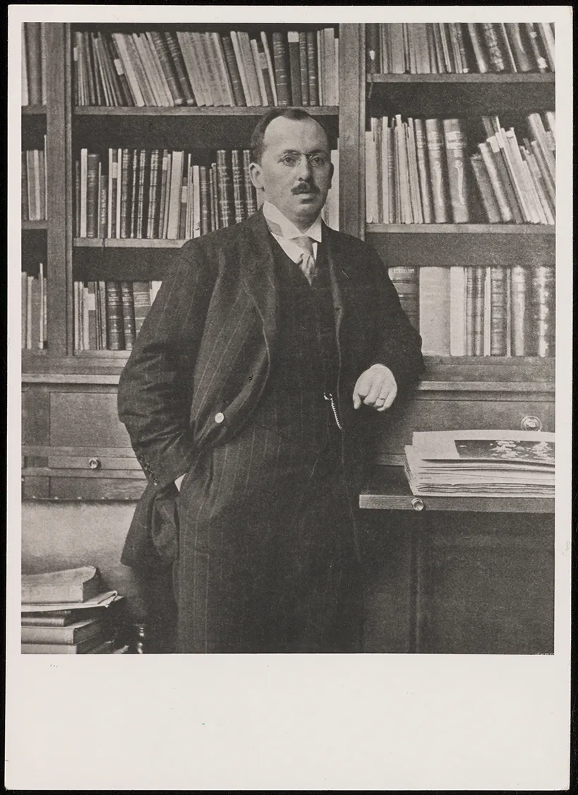 Portretfoto van Wilhelm Martin voor een boekenkast in de directeurskamer van het Mauritshuis